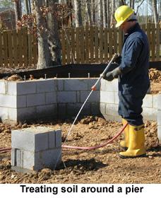 Person in rubber boots and hard hat sprays the ground
